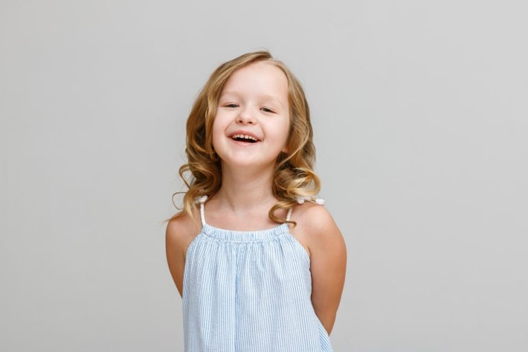 A young girl in a blue dress smiling